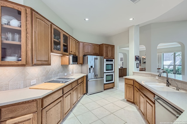 kitchen with decorative backsplash, stainless steel appliances, light tile patterned floors, and sink