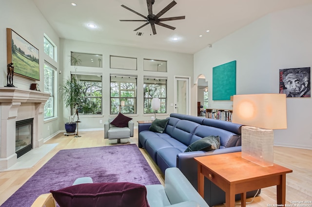 living room featuring ceiling fan, light wood-type flooring, and a premium fireplace