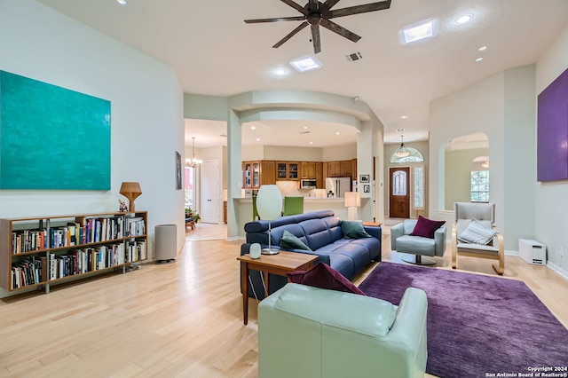 living room featuring ceiling fan with notable chandelier and light hardwood / wood-style flooring