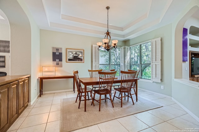 dining space with a notable chandelier, a raised ceiling, and light tile patterned floors