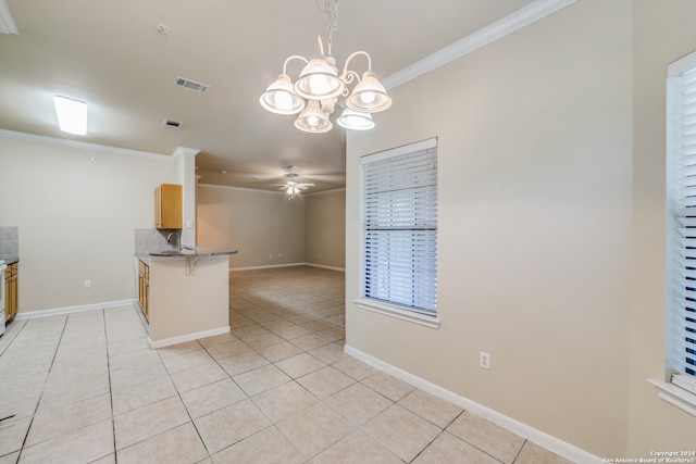 interior space with pendant lighting, ornamental molding, kitchen peninsula, a breakfast bar area, and ceiling fan with notable chandelier