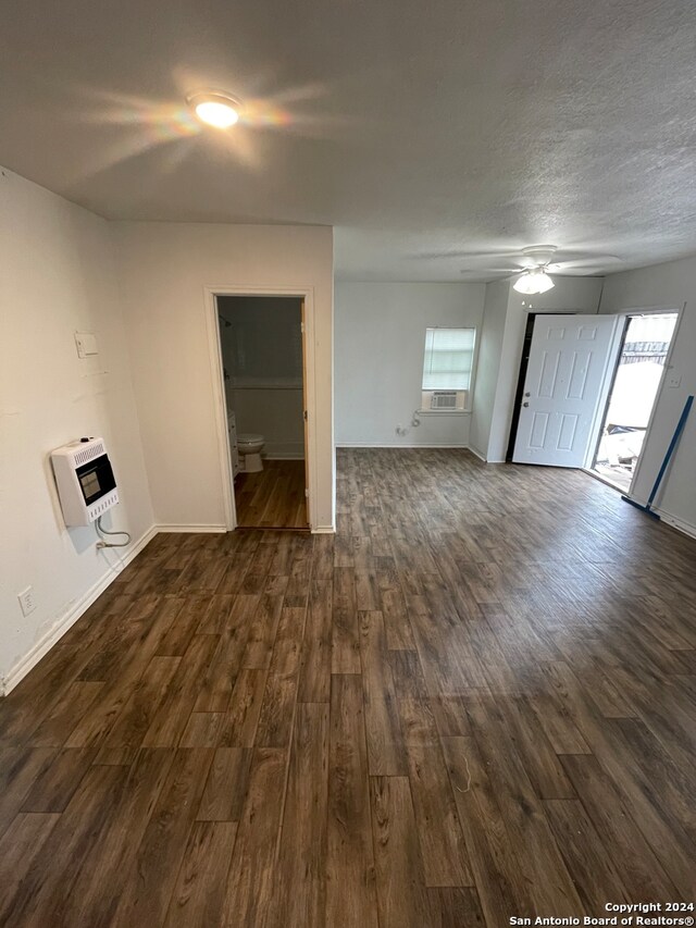 unfurnished living room with heating unit, cooling unit, ceiling fan, and dark hardwood / wood-style flooring