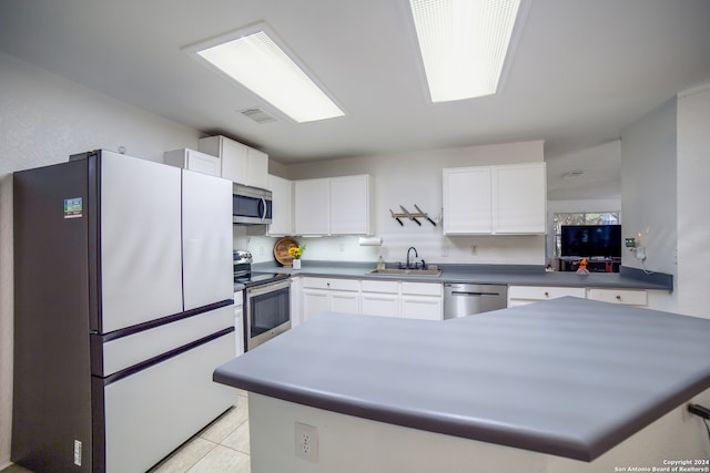 kitchen with stainless steel appliances, white cabinets, light tile patterned floors, and sink