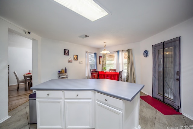 kitchen with hanging light fixtures, light tile patterned flooring, a center island, and white cabinets