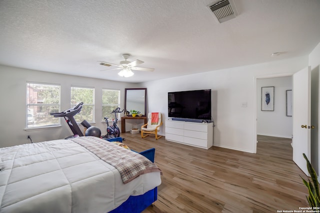 bedroom featuring a textured ceiling, wood-type flooring, and ceiling fan