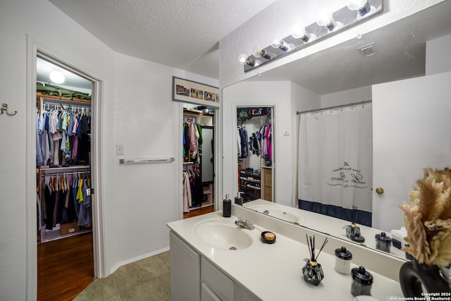 bathroom with a textured ceiling, tile patterned flooring, and vanity