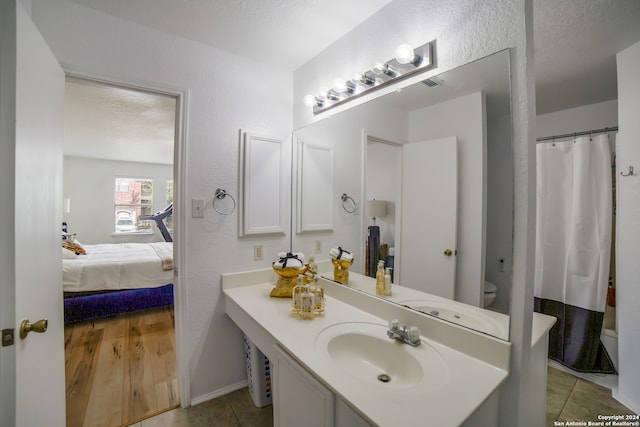 bathroom with vanity, tile patterned flooring, toilet, and a textured ceiling