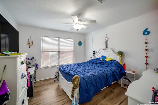 bedroom featuring light hardwood / wood-style floors, ceiling fan, and a textured ceiling