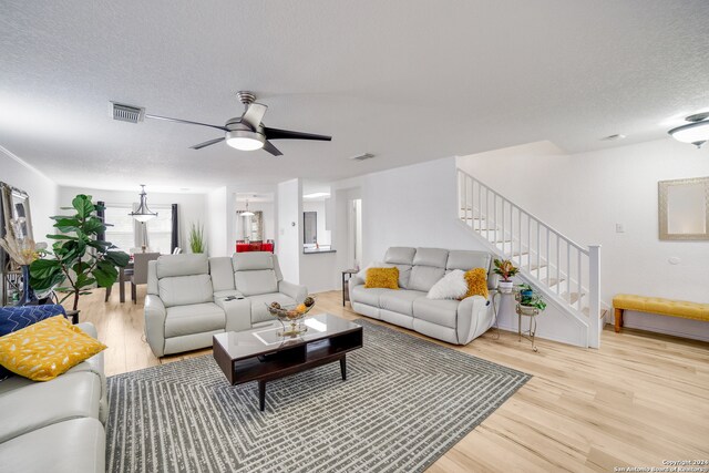 living room featuring ceiling fan, a textured ceiling, and light hardwood / wood-style flooring