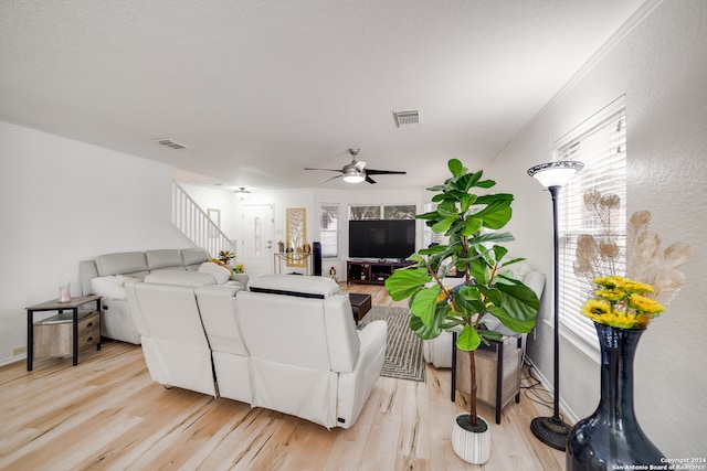 living room with light wood-type flooring, ceiling fan, and crown molding