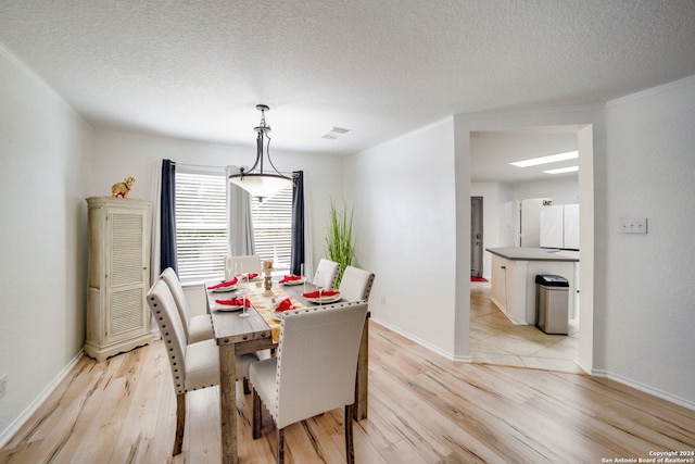 dining room featuring a skylight, light hardwood / wood-style floors, and a textured ceiling