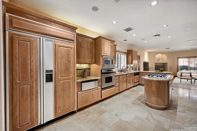 kitchen with sink, kitchen peninsula, a kitchen island, backsplash, and built in appliances