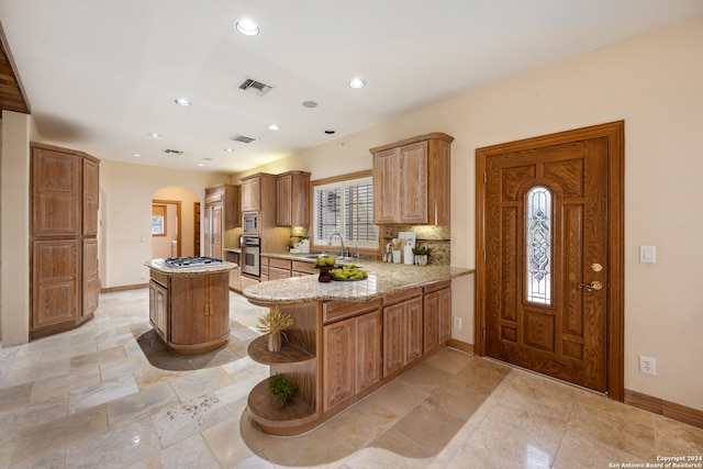 kitchen featuring a center island, tasteful backsplash, sink, kitchen peninsula, and stainless steel appliances