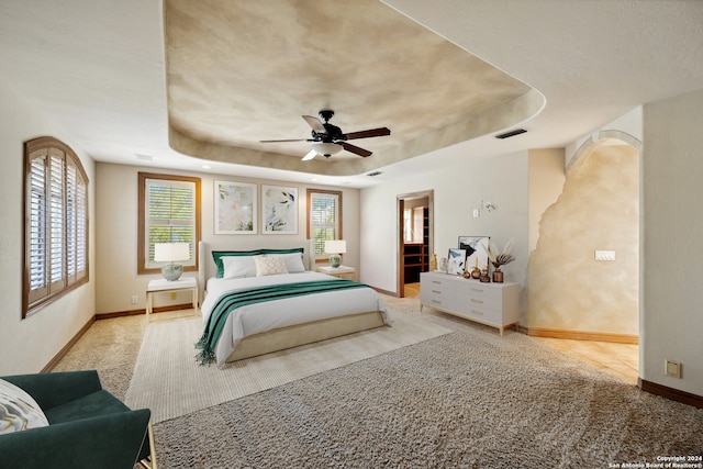 carpeted bedroom featuring a tray ceiling and ceiling fan