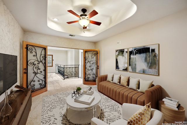 carpeted living room featuring a tray ceiling and ceiling fan