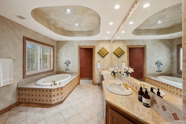 bathroom with tile patterned flooring, tiled tub, vanity, and a tray ceiling