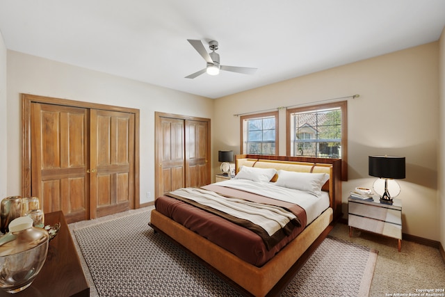 carpeted bedroom with ceiling fan and multiple closets