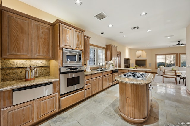 kitchen with ceiling fan, light stone counters, sink, kitchen peninsula, and appliances with stainless steel finishes