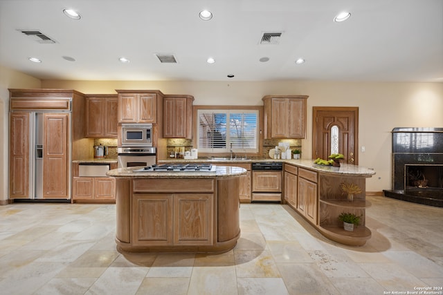 kitchen with a center island, built in appliances, sink, and tasteful backsplash