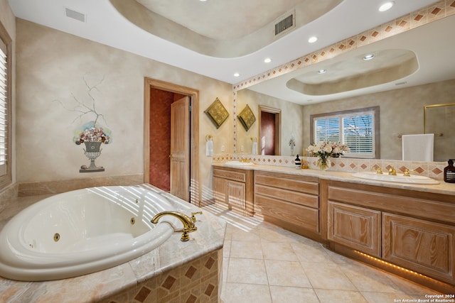 bathroom with vanity, a relaxing tiled tub, a raised ceiling, and tile patterned floors