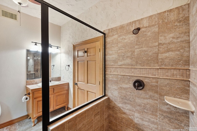 bathroom with vanity and tiled shower