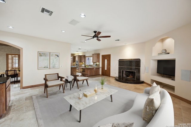 living room with ceiling fan and a tile fireplace