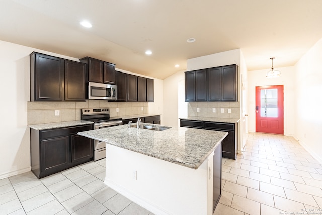 kitchen with an island with sink, backsplash, stainless steel appliances, decorative light fixtures, and sink