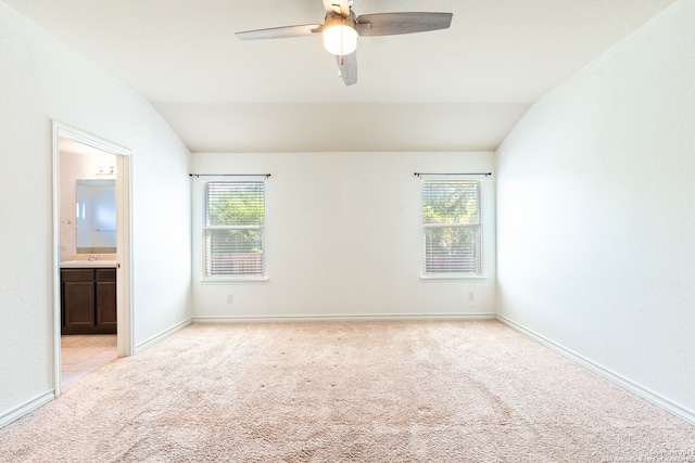 carpeted empty room with vaulted ceiling, ceiling fan, and a healthy amount of sunlight