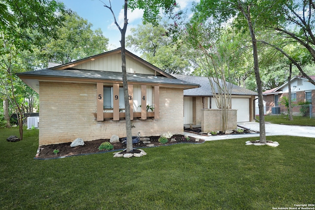 view of front of house with a garage, central AC unit, and a front lawn