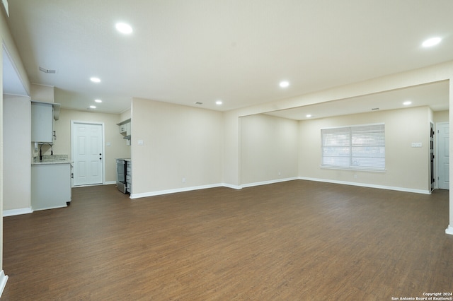 unfurnished living room featuring sink and dark wood-type flooring