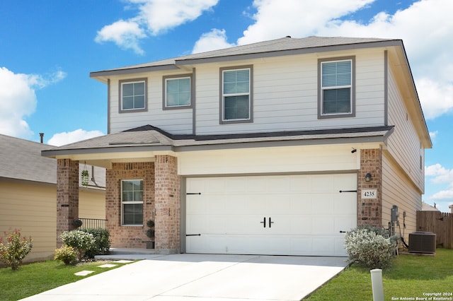 view of front of home with a garage, a front lawn, and central AC