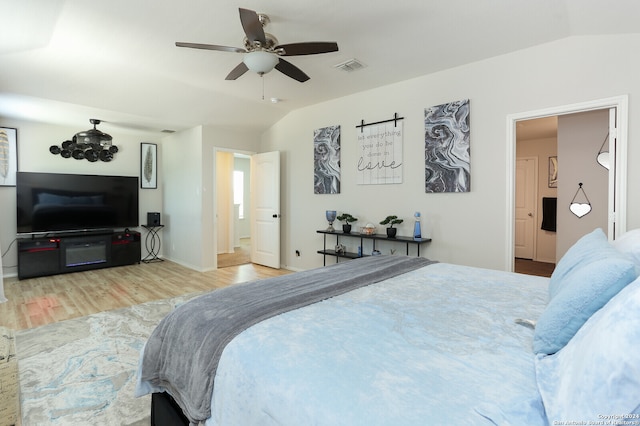 bedroom featuring wood-type flooring, vaulted ceiling, ensuite bath, and ceiling fan