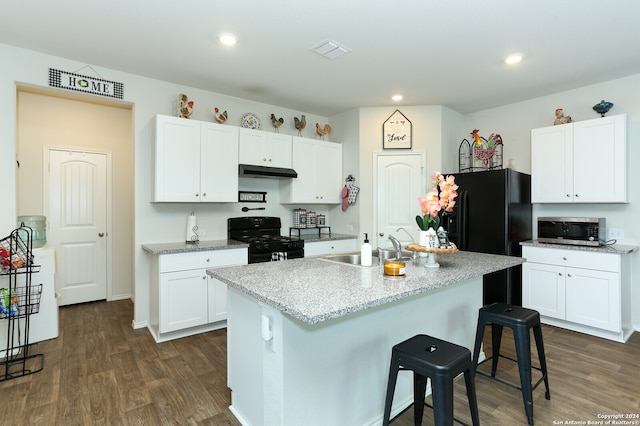 kitchen with black gas stove, white cabinets, dark wood-type flooring, and a kitchen island with sink