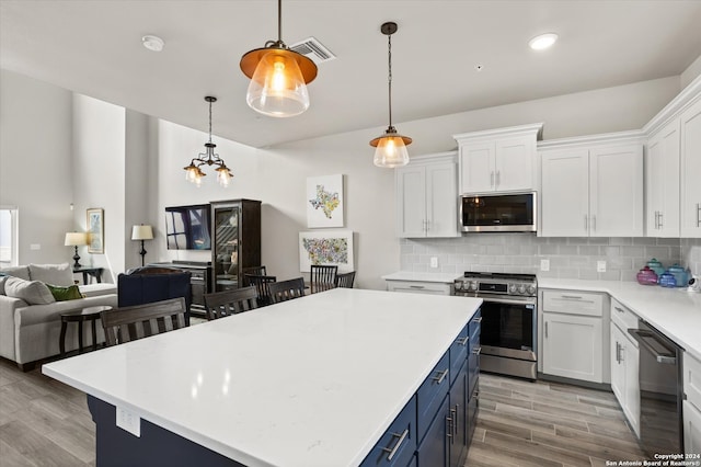 kitchen with blue cabinets, white cabinetry, appliances with stainless steel finishes, a center island, and light wood-type flooring