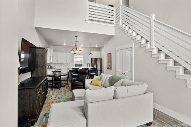 living room with an inviting chandelier, a high ceiling, and hardwood / wood-style floors