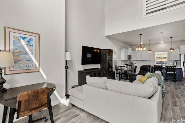 living room with an inviting chandelier, light hardwood / wood-style floors, and a high ceiling