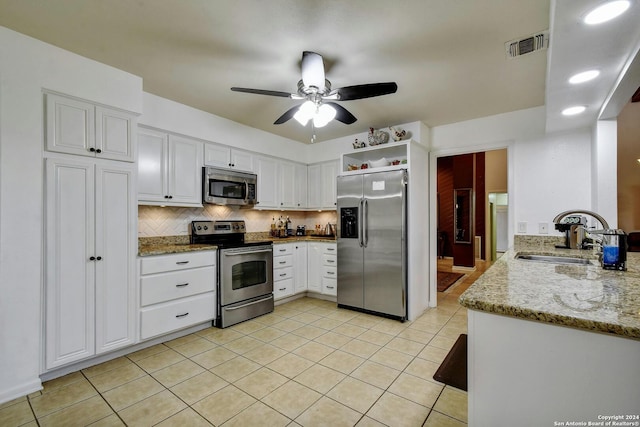 kitchen with light stone counters, sink, white cabinets, stainless steel appliances, and ceiling fan