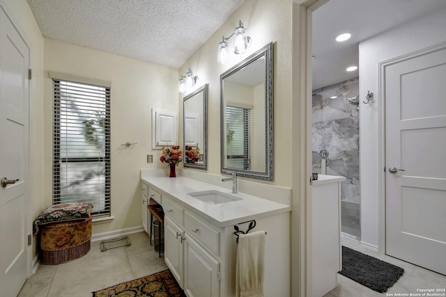 bathroom featuring vanity, a tile shower, a textured ceiling, and tile patterned floors