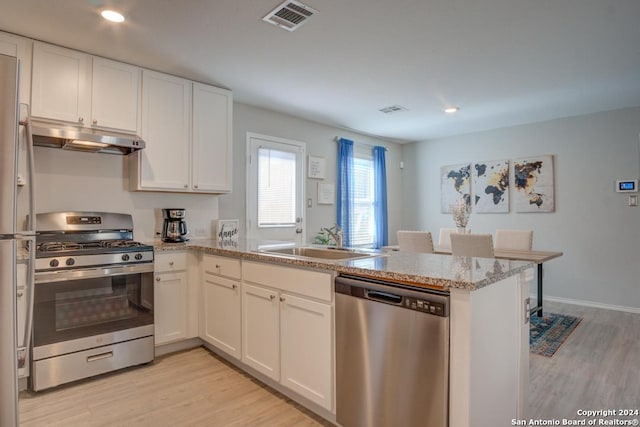 kitchen with sink, appliances with stainless steel finishes, light wood-type flooring, and kitchen peninsula