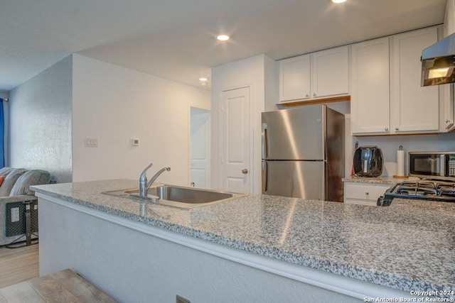 kitchen with sink, white cabinets, light hardwood / wood-style flooring, appliances with stainless steel finishes, and light stone countertops