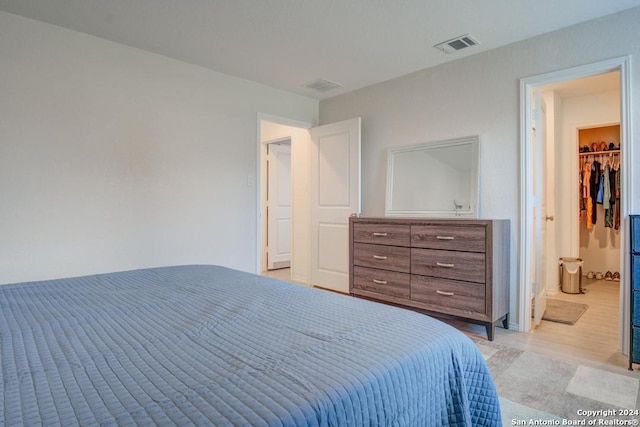 bedroom featuring light hardwood / wood-style floors, a walk in closet, and a closet