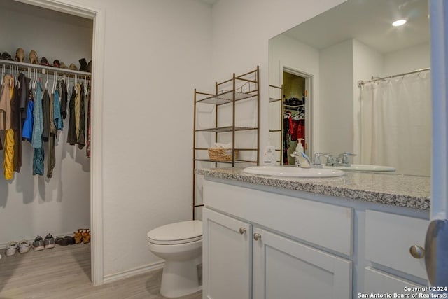 bathroom with hardwood / wood-style floors, vanity, and toilet