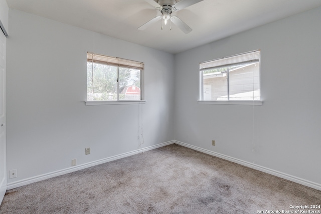 carpeted spare room featuring ceiling fan and a wealth of natural light