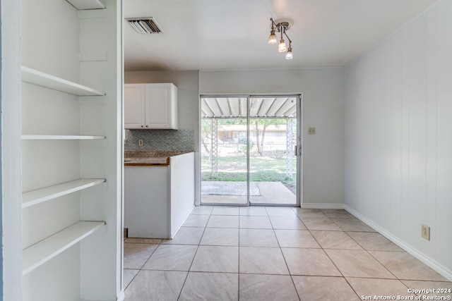 kitchen featuring decorative backsplash, light tile patterned floors, and white cabinets