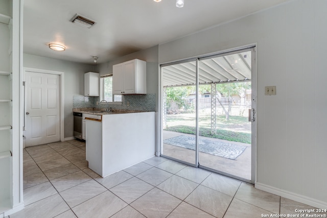 kitchen with decorative backsplash, light tile patterned flooring, white cabinetry, and sink