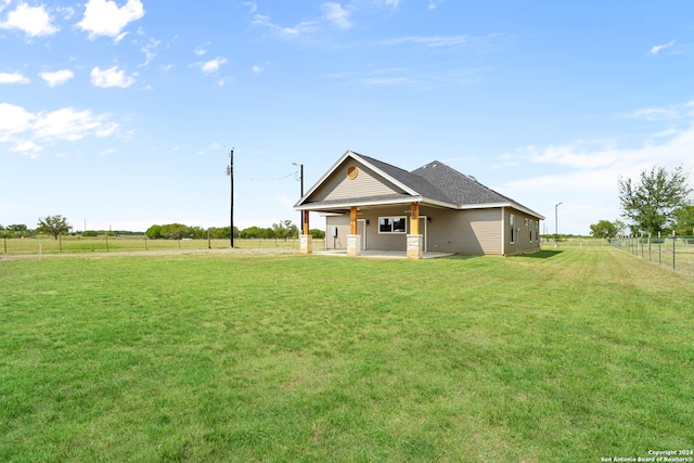 back of property with a rural view and a yard