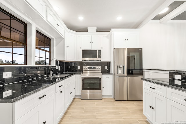 kitchen featuring dark stone counters, white cabinetry, appliances with stainless steel finishes, and sink