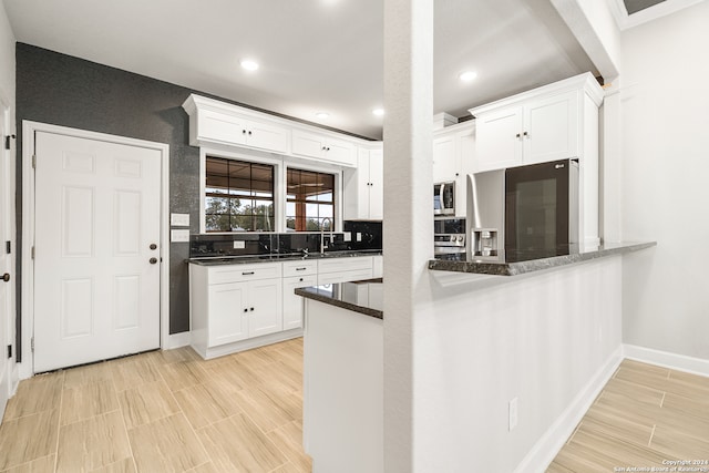 kitchen with decorative backsplash, appliances with stainless steel finishes, dark stone counters, and white cabinetry