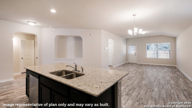 kitchen featuring an island with sink, pendant lighting, light wood-type flooring, stainless steel dishwasher, and sink