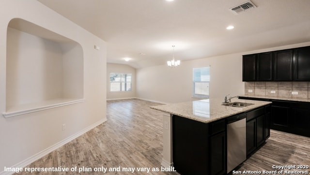 kitchen with dishwasher, sink, decorative backsplash, light hardwood / wood-style flooring, and a center island with sink